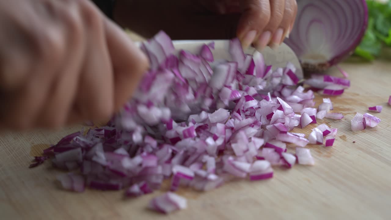 Chopping red onions on cutting board and special ingredients to cook a meal two cans of beans rice plantain avocado red onion and cilantro