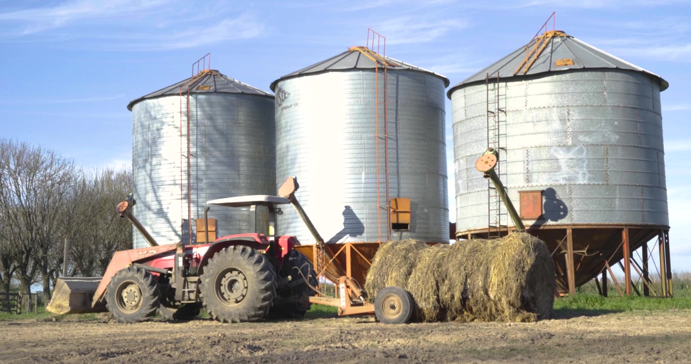 Traktor bei Getreidesilos an einem sonnigen Bauernhoftag.