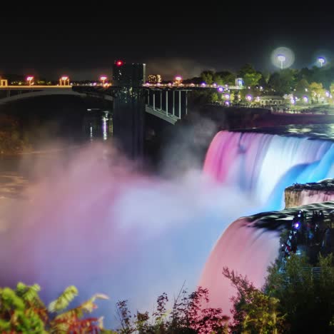 niagara falls at night with the glow of the city lights behind