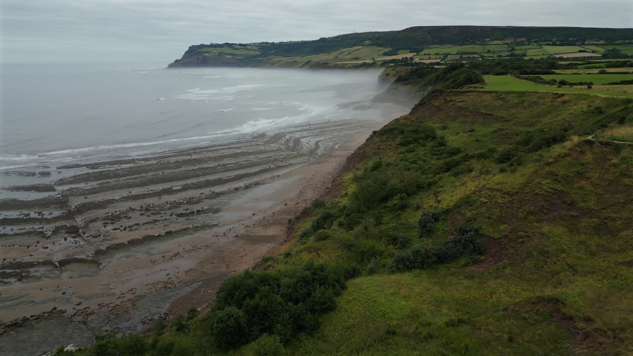 Establishing Aerial Drone Shot Along North Yorkshire Coast in Mist at Low Tide Near Robin Hood's Bay