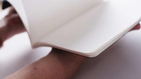 close up of hand leafing through book with copy space on white background in slow motion