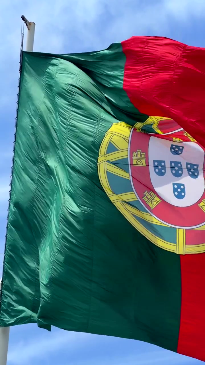 Bandera de Portugal ondeando al viento contra un cielo azul