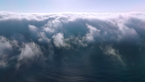 blue ocean water covering with thick fog. bright sun shining on the top of hazy cloudscape. aerial view.