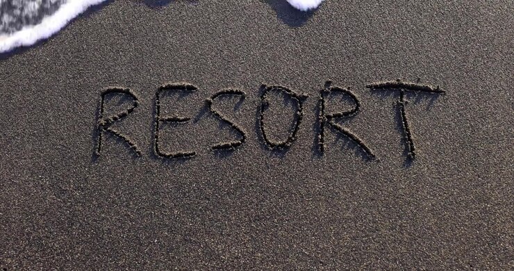 Word resort washed away with foamy ocean wave upper view