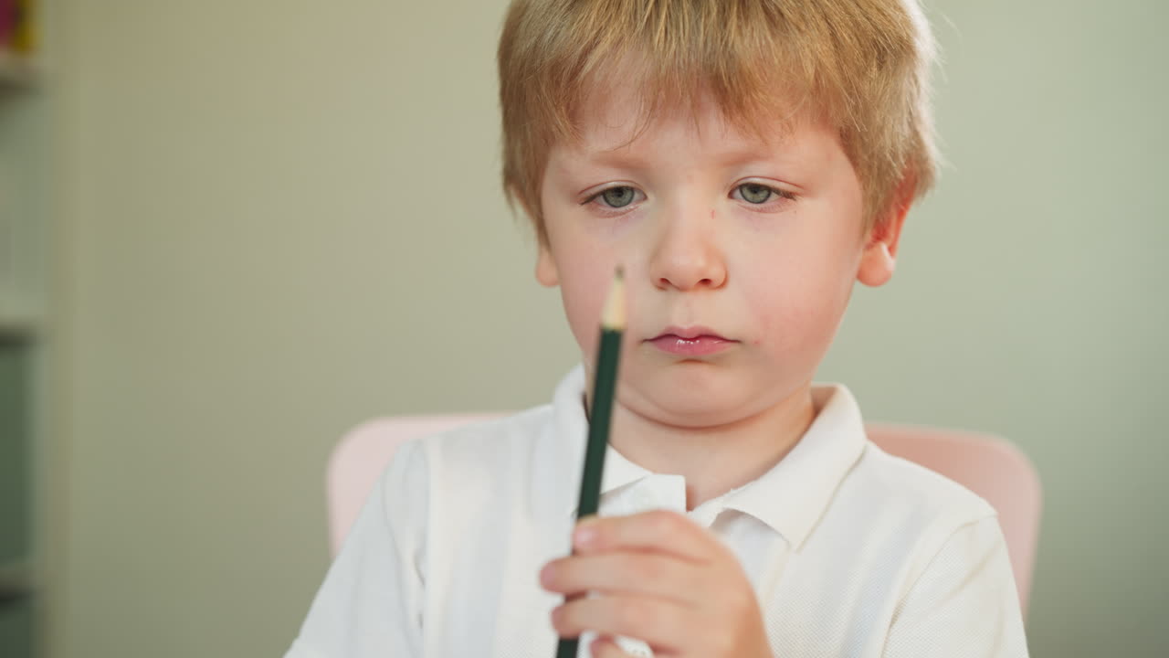 심각한 유아 소년은 손에 녹색 연필 연필을 공부