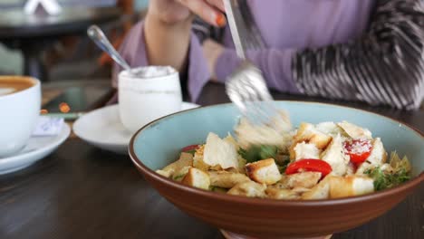 mujer comiendo ensalada de césar en un café