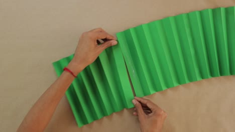 male works with zigzag green paper, gluing for traditional mexican fan