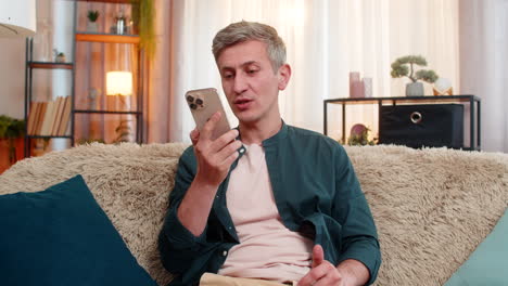 Young man argues angrily on smartphone and gestures emotionally during loud stressful phone call