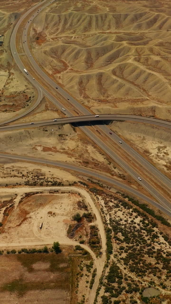 Roads crossing in the desert of Colorado, USA. Cars running fast by the highways among the sandy dunes. Aerial view. Vertical video