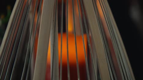 close-up of a glowing candle inside a bamboo lantern