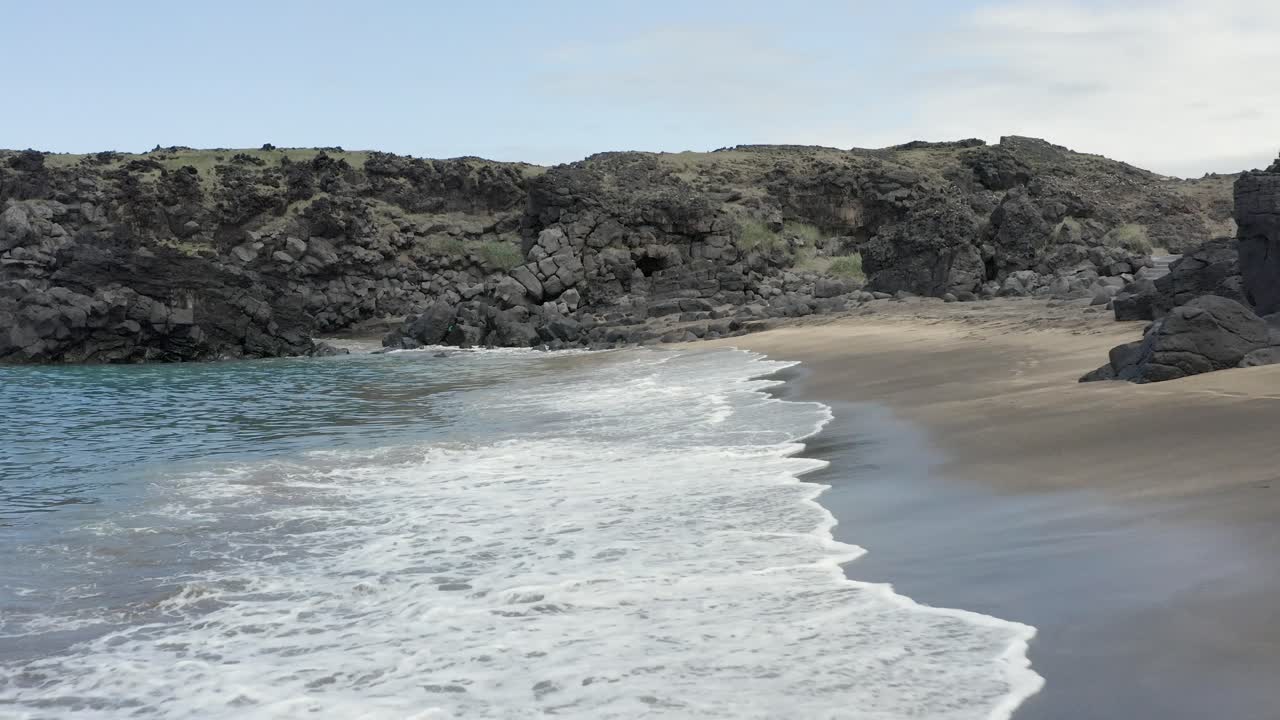 пустой уединенный пляж с мягкими волнами, разбивающимися о песчаный берег, низкая антенна