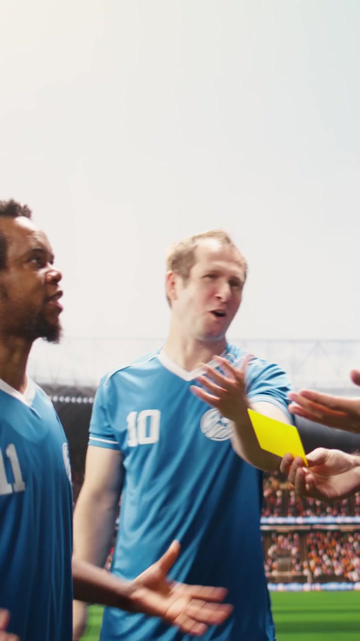 Vertical Video Man referee raising yellow card as warning for angry player on stadium pitch