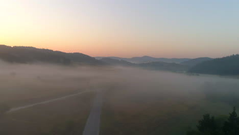 a road to a misty field in a mountainous area