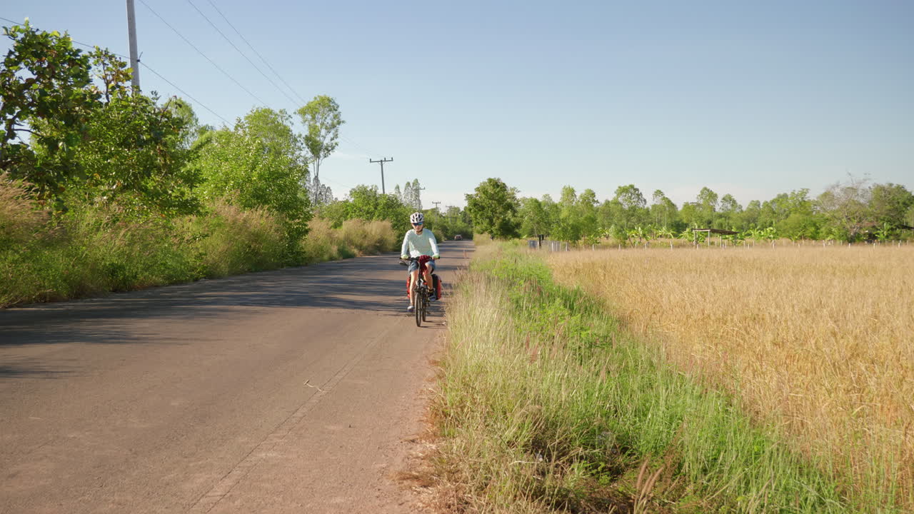태국 시골 지역을 가로지르는 접이식 자전거를 타고 운동복을 입은 솔로 아시아 여성