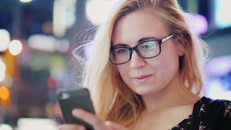 mujer usando teléfono en la ciudad por la noche