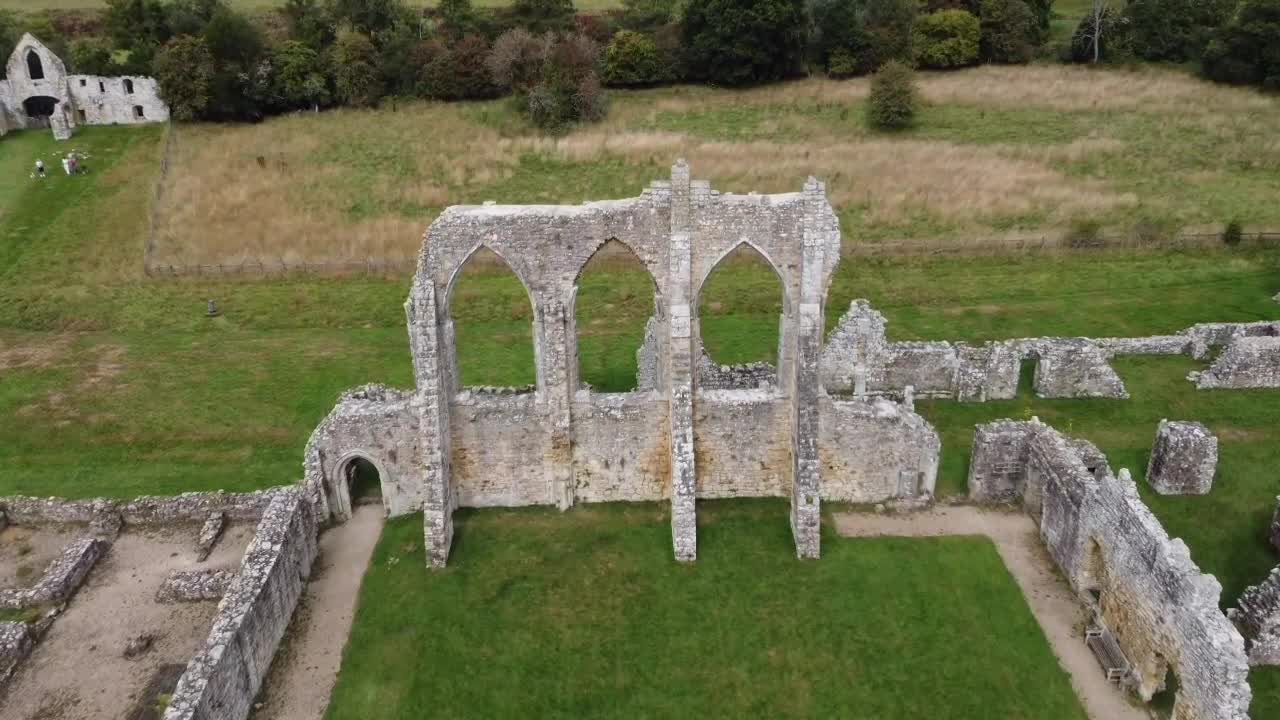 Aerial view flying toward the arches of Old Bayham Abbey, Kent. Historic medieval ruins framed by lush countryside, ideal for travel, heritage, or cinematic projects