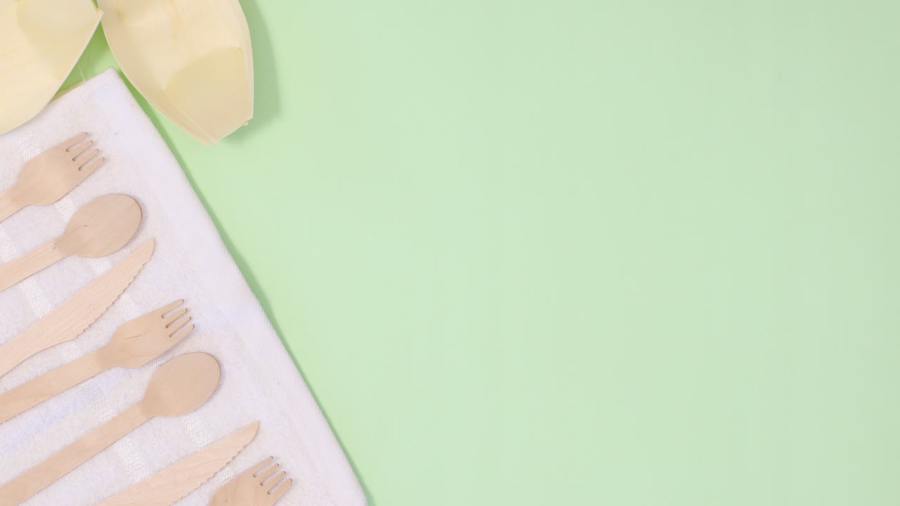 utensilios ecológicos de cero residuos se mueven en tela blanca en el lado izquierdo del fondo verde claro.