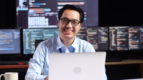 smiling programmer in front of multiple computer screens