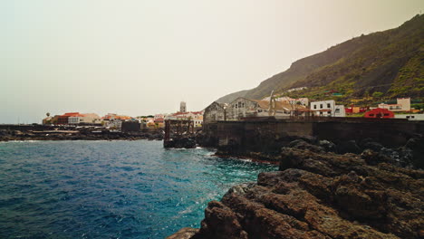 panoramic view of the small town of garachico in tenerife, canary islands, spain. view of the turquoise sea and the black volcanic rocky coastline surrounding the local town.