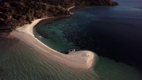 Beautiful-tropical-island-sandbar,-curved-beach,-turquoise-sea,-waves-and-boats