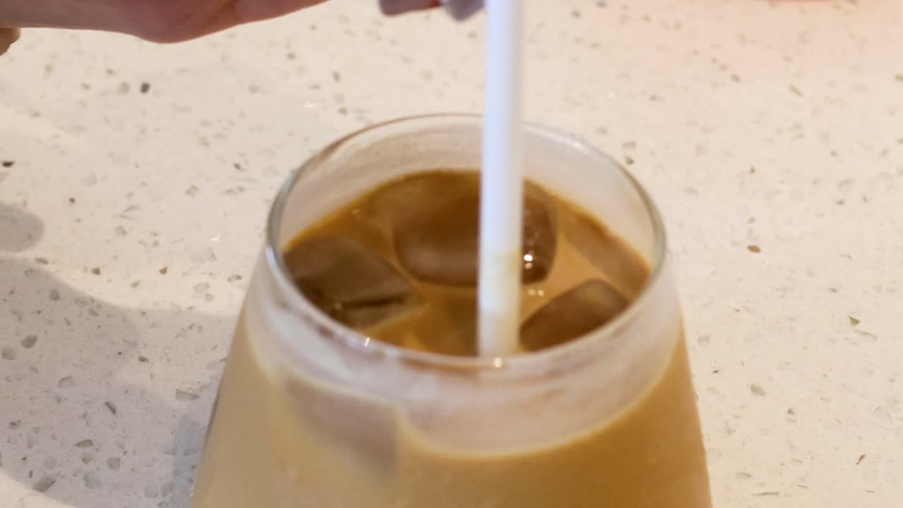 A straw stirring iced coffee in a glass