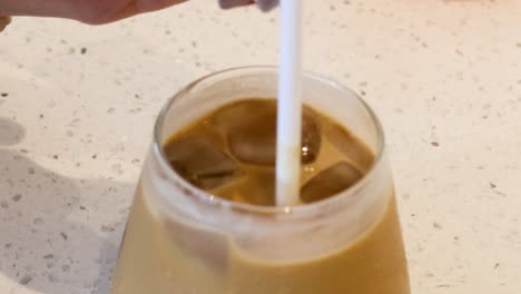 a straw stirring iced coffee in a glass