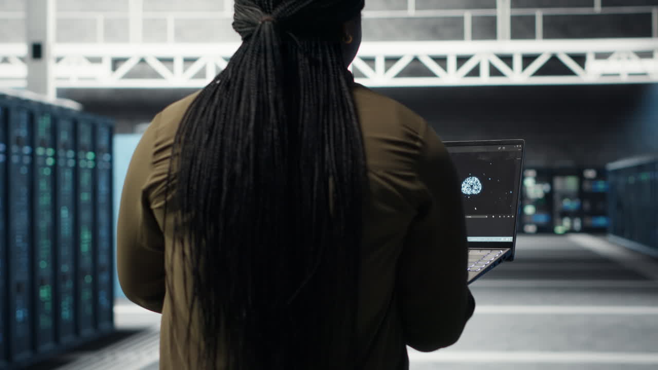 Engineer in server hub using laptop to upgrade rigs using AI deep learning