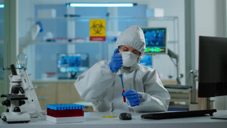 técnico científico en traje de ppe usando micropipeta y placa de petri analizando una muestra de sangre