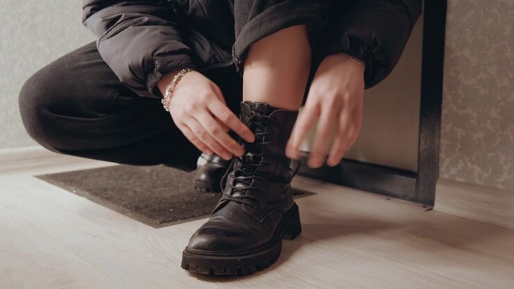 Mani che sistemano le calzature per un viaggio all'aperto. Momento di preparazione mentre gli stivali vengono allacciati. Periodo di preparazione concentrata con le mani che stringono i lacci e ispezionano accuratamente le suole