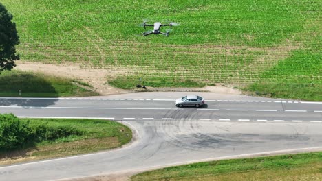 aerial view of quadcopter drone with camera flying above road and observes traffic on sunny summer day