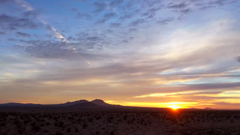 vista romántica perfecta del desierto de mojave durante una puesta de sol dorada o un amanecer: retroceda la vista panorámica de gran angular con las montañas en silueta