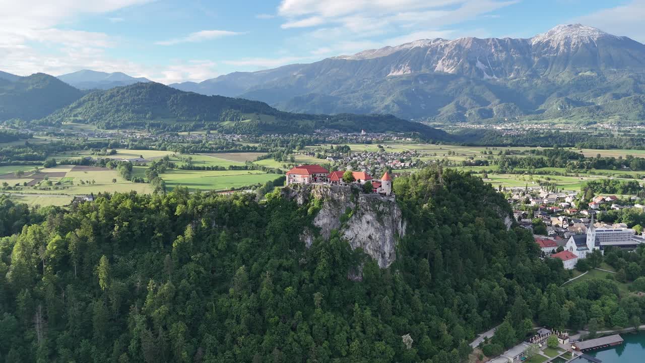 Ampia ripresa aerea con drone verso il castello di Bled con il lago sotto la scogliera, giornata di sole in Slovenia