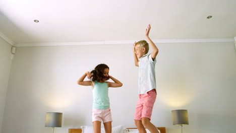 siblings having fun on bed in bedroom