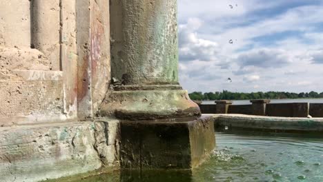 water droplets in old baroque-style fountain with lake view in the background