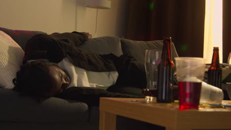 Man-Lying-Passed-Out-On-Sofa-After-Drinking-Alcohol-At-House-Party-Suffering-With-Hangover-1