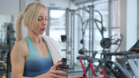 woman drinking protein shake in gym