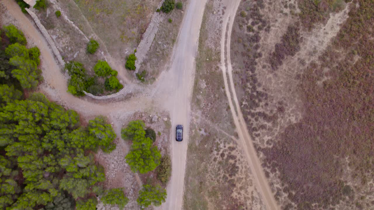 vista aérea de pájaro siguiendo el coche que se mueve a través de la carretera regional a través del entorno natural, paisaje seco con poca vegetación, concepto de conducción fuera de carretera, ubicación francia
