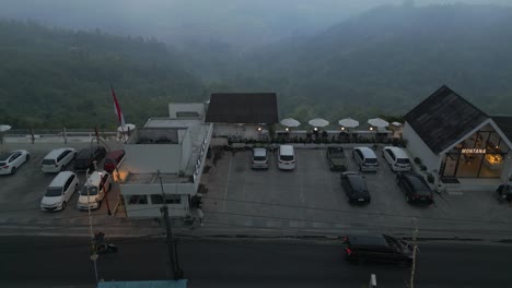 drone flying up high above the mountain road with a parking lot on the edge of a cliff in north of bali