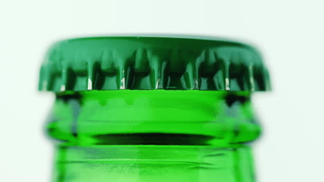 the neck of a bottle of beer is covered with a metal lid on a white background