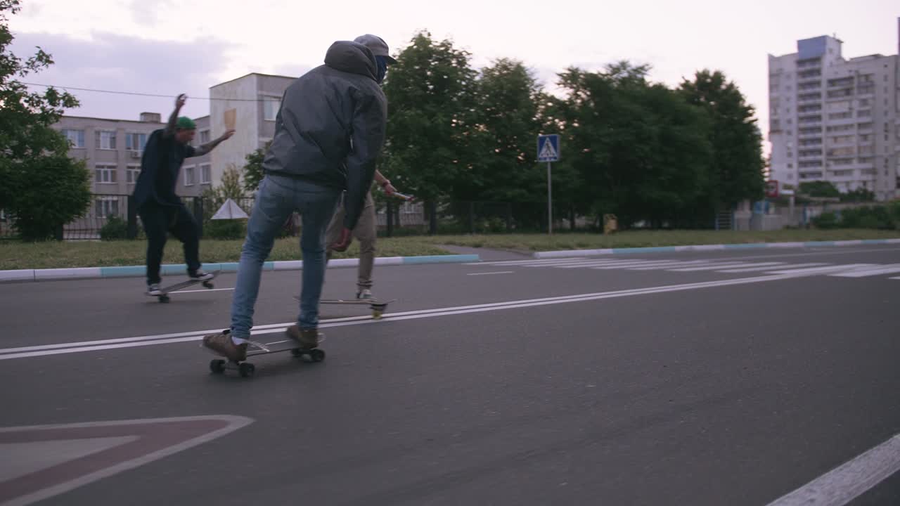 grupo de jóvenes patinando en la carretera temprano en la mañana, toma cinematográfica, cámara lenta