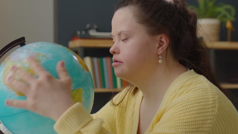 girl with down syndrome examining globe