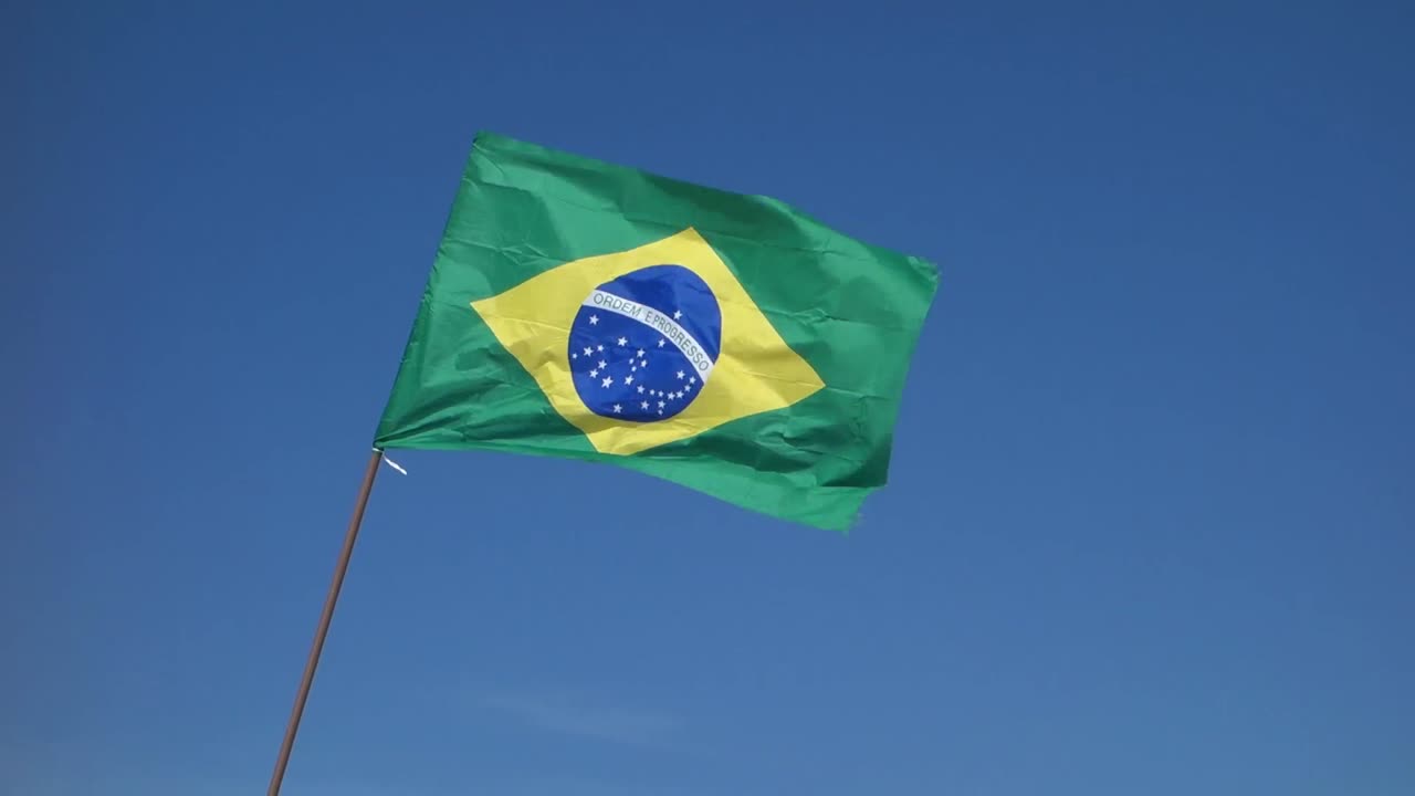 Bandeira brasileira tremulando ao vento, com fundo de céu azul