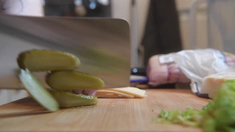 preparándose para el almuerzo cortando algunos pepinillos encurtidos con un cuchillo muy grande e inteligente
