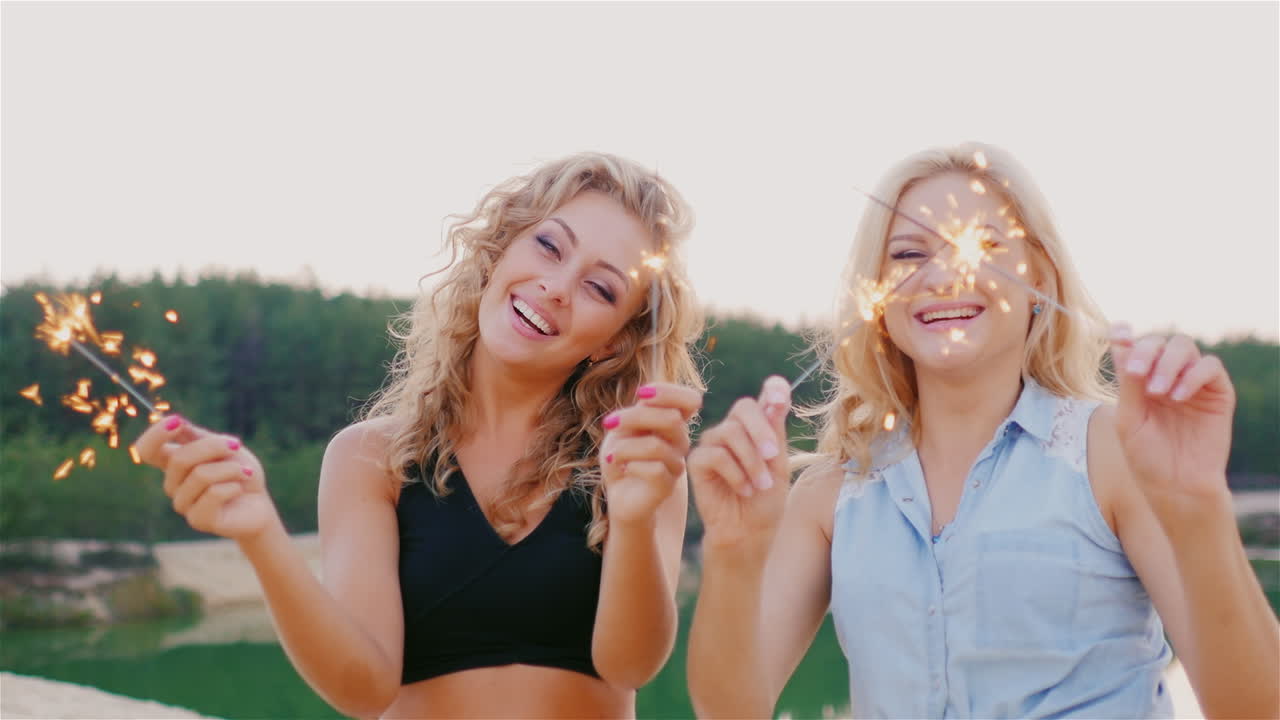 две привлекательные женщины с искрами смеются на пляже