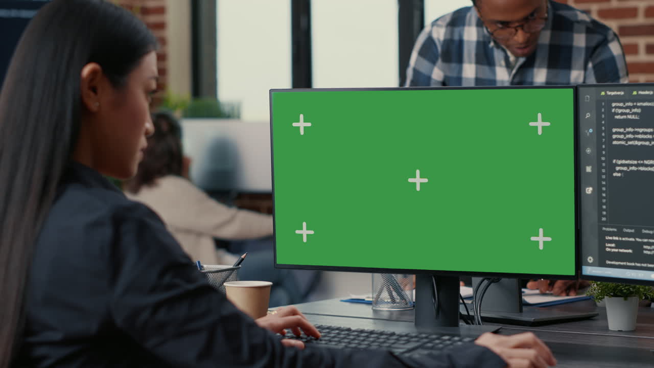 Focus on computer screen with green screen chroma key mockup in front of asian programer writing code