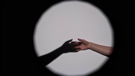 hand and shadow reaching in a spotlight