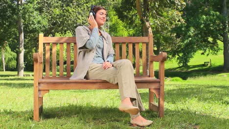 Young-woman-listening-to-music-on-a-bench