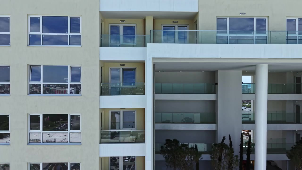 Vista de un edificio moderno con balcón y cielo azul claro al fondo durante las horas del día.