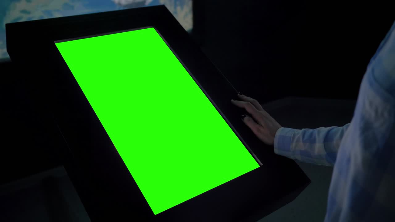mujer mirando un quiosco de exhibición verde en blanco en una exposición - concepto de pantalla verde