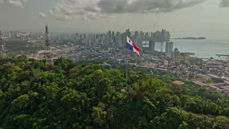 panama city aerial v67 cinematic low level flyover ancon hill with wind blowing the national flag on hilltop with coastal downtown cityscape in the background - shot with mavic 3 cine - march 2022